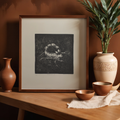 A framed black-and-white art print featuring a detailed illustration of a crab, styled on a wooden table with ceramic vases and bowls against a warm brown wall.